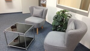 Una habitación con un sillón gris, un reposapiés a juego y una mesa con cubierta de vidrio.