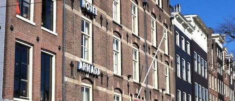 A hotel with a sign reading "Hotel Armada" on a brick building with multiple windows and a red awning.