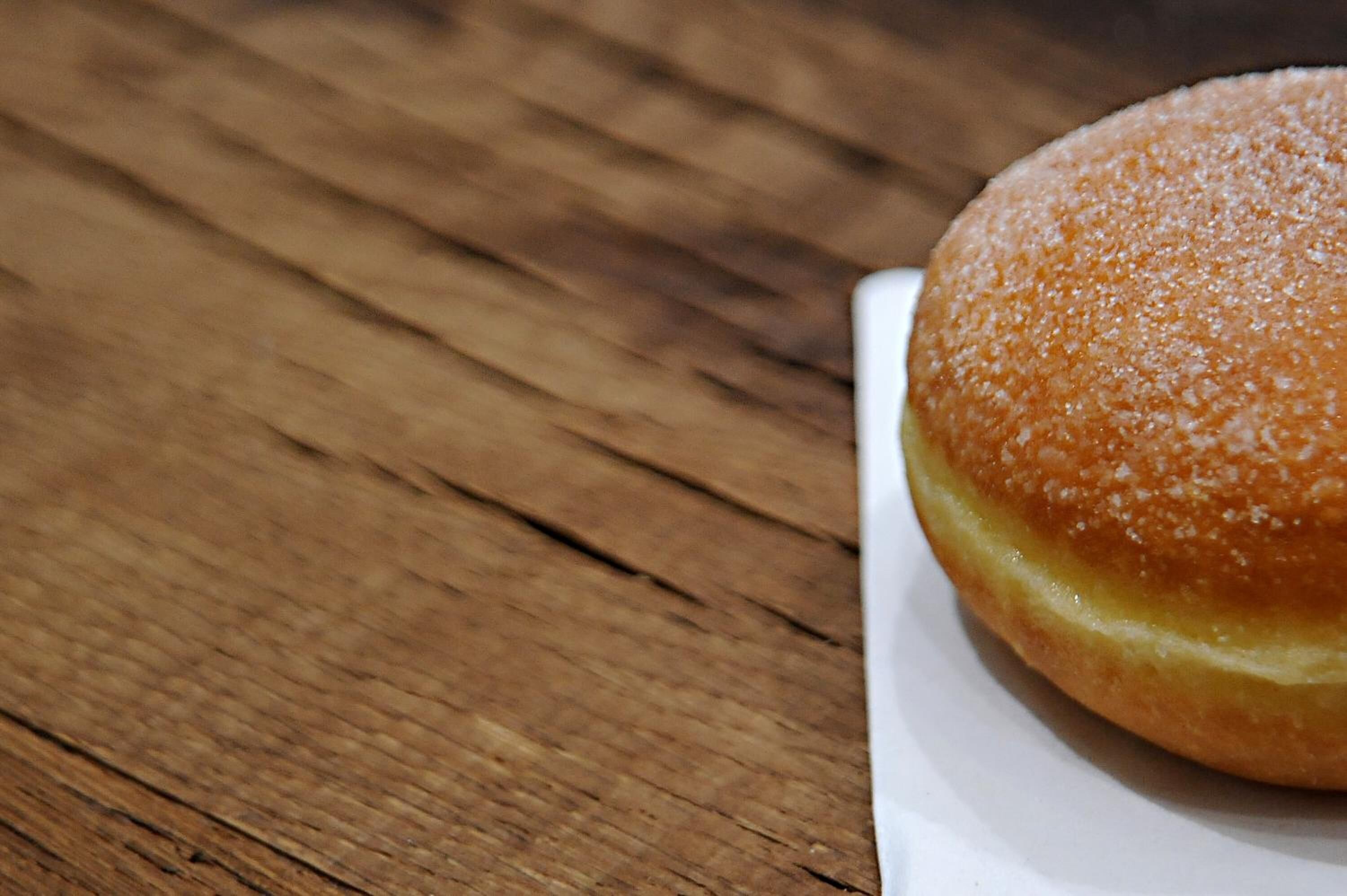 A round, sugar-coated pastry on a white plate.