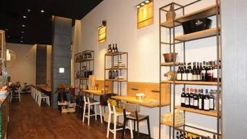 Ein Restaurantinneres mit Holzboden, weißen Stühlen und Regalen mit Weinflaschen.
