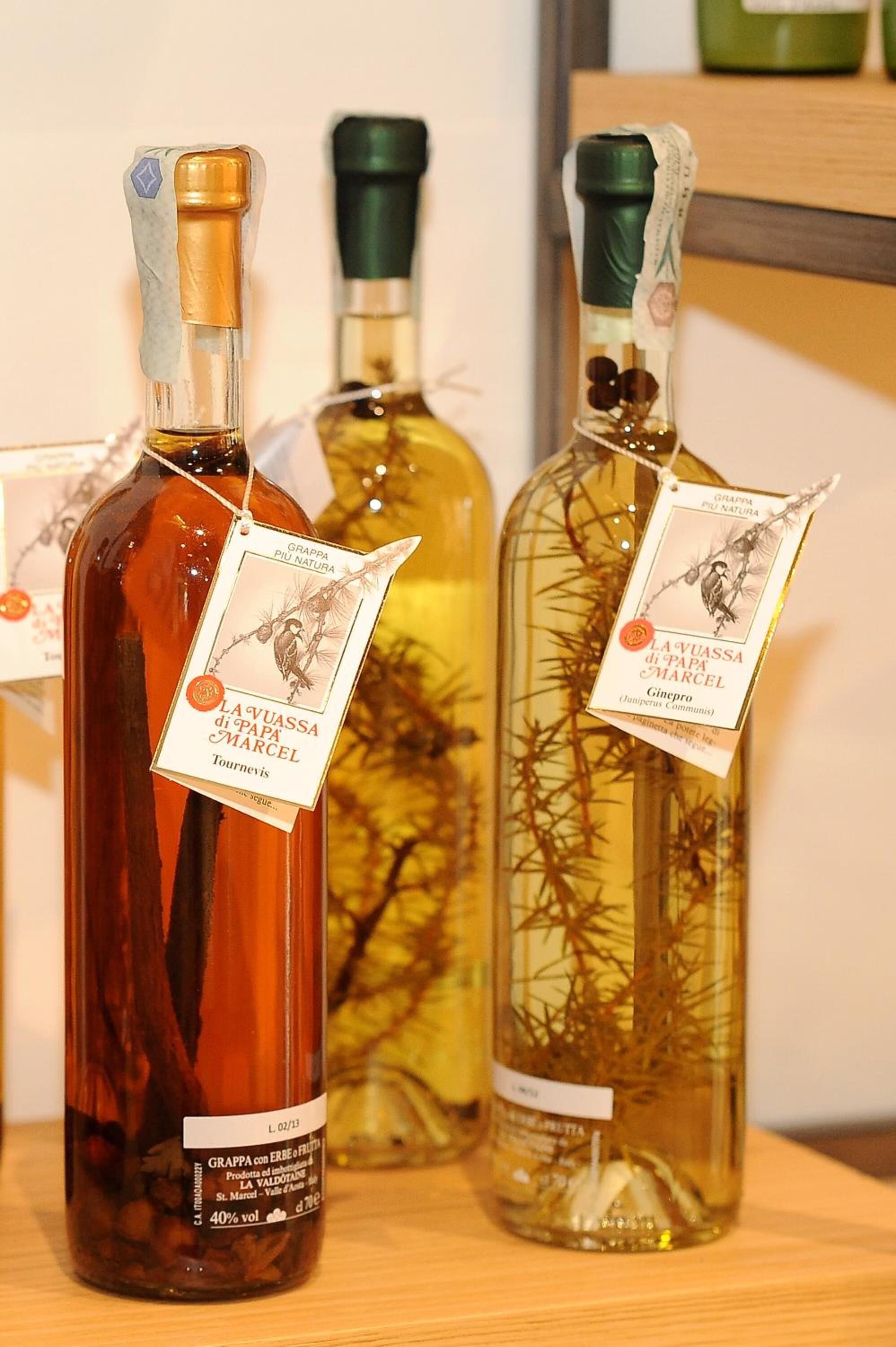 Three bottles of wine with labels, placed on a wooden surface.