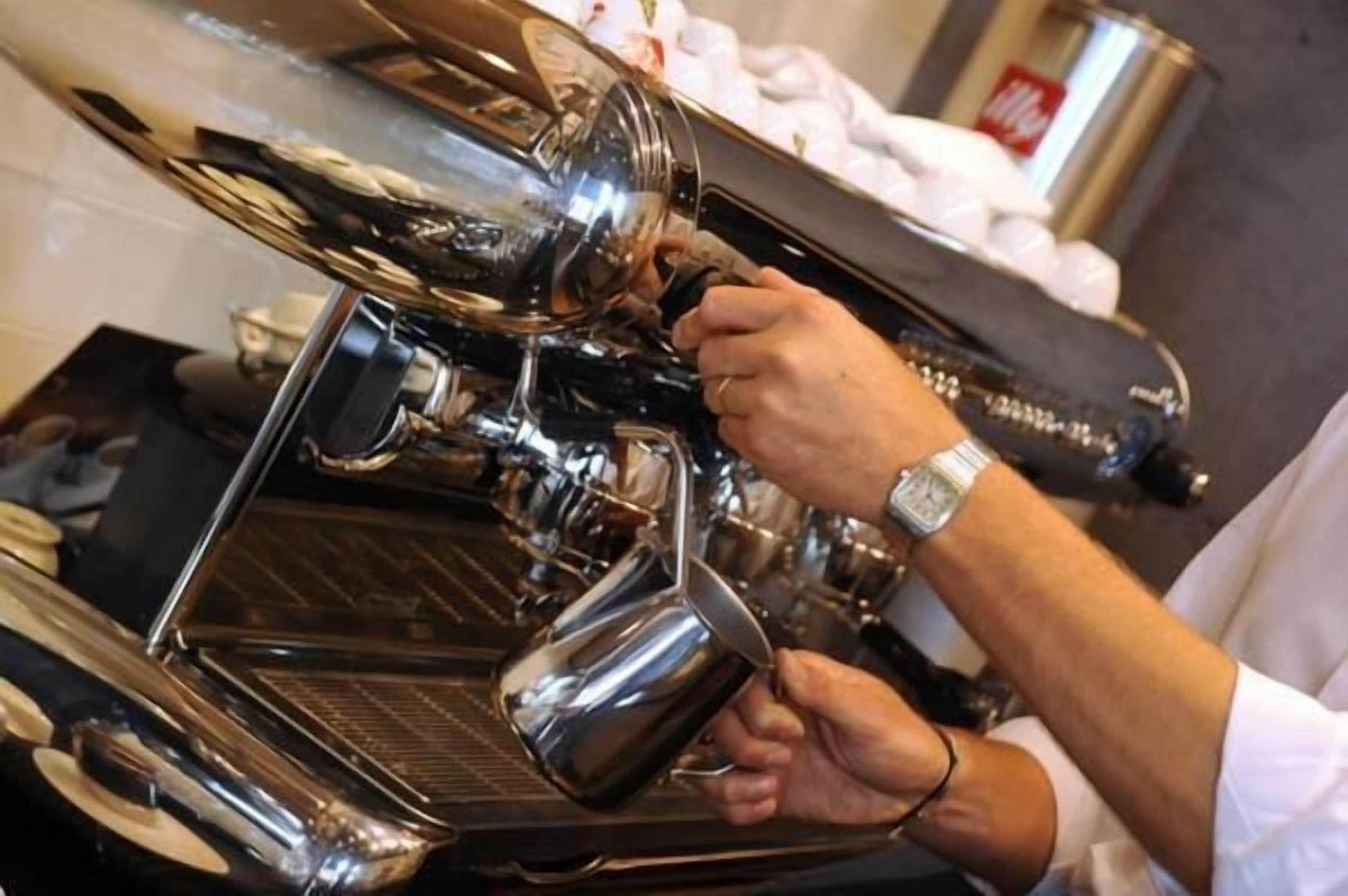 Una persona operando una máquina de café, probablemente en una cafetería o restaurante.
