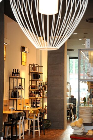 A restaurant interior with wooden tables and chairs, shelves with bottles, and a hanging light fixture. - Hotel Rivarolo (Rivarolo Canavese)