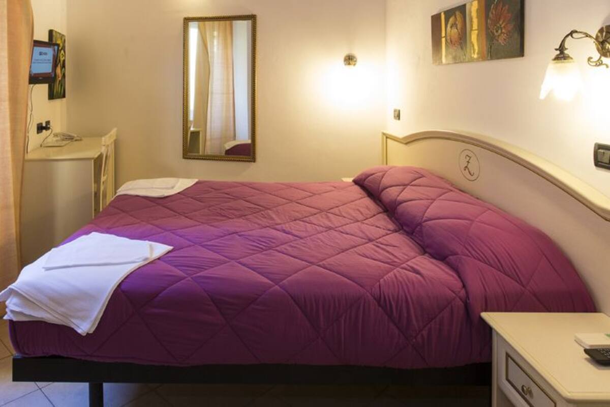 A bedroom with a bed, bedside tables, a mirror, and a nightstand.