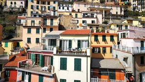 Une ville pittoresque, construite à flanc de colline, avec des bâtiments aux couleurs vives, un imposant beffroi et un mélange de balcons et de terrasses.