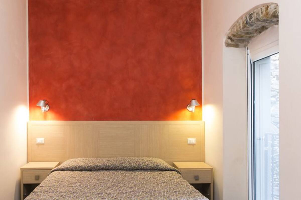 A hotel room with a bed centered between two nightstands, each with a lamp.