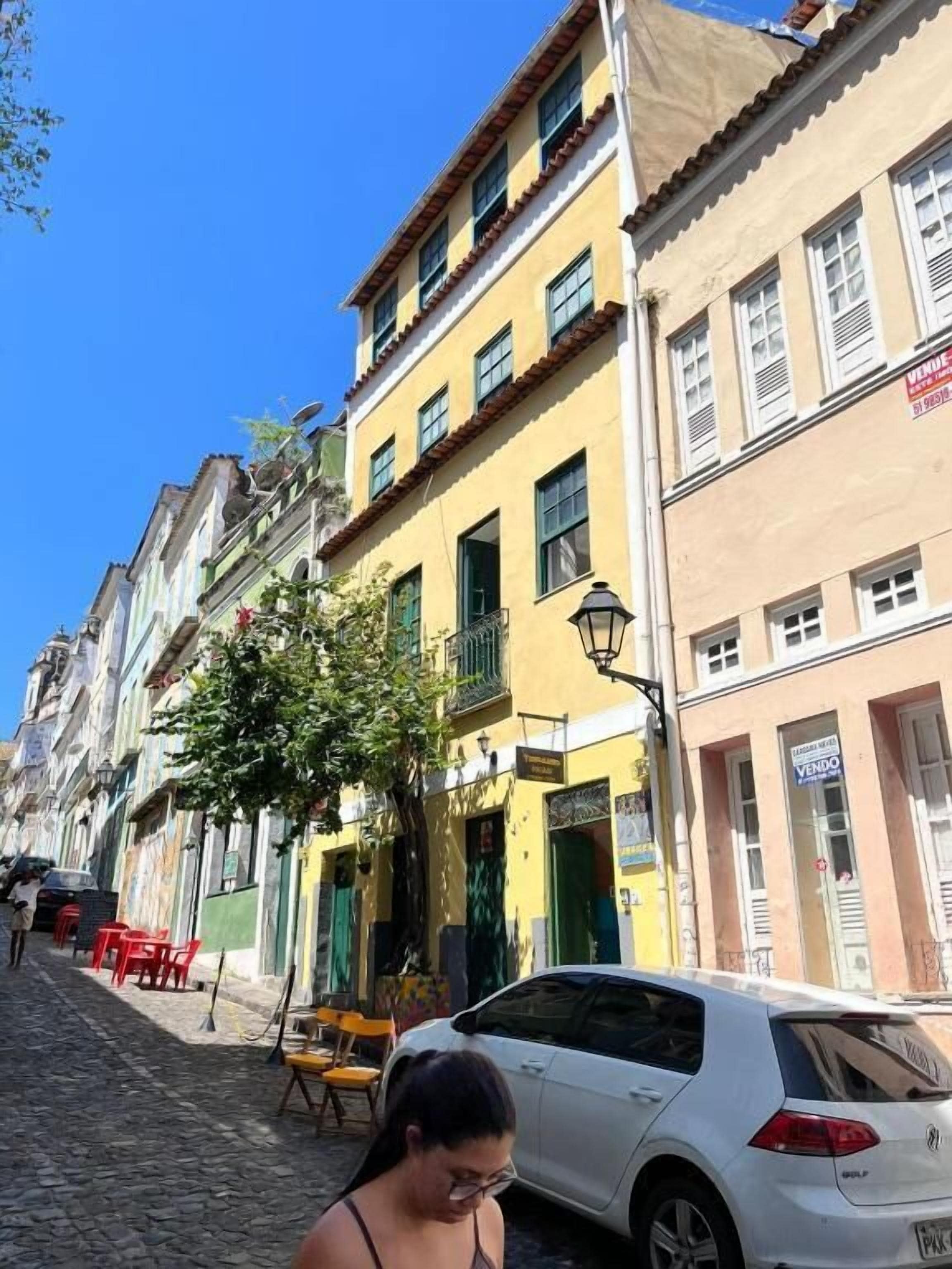 A street with buildings, a parked car, and outdoor seating.