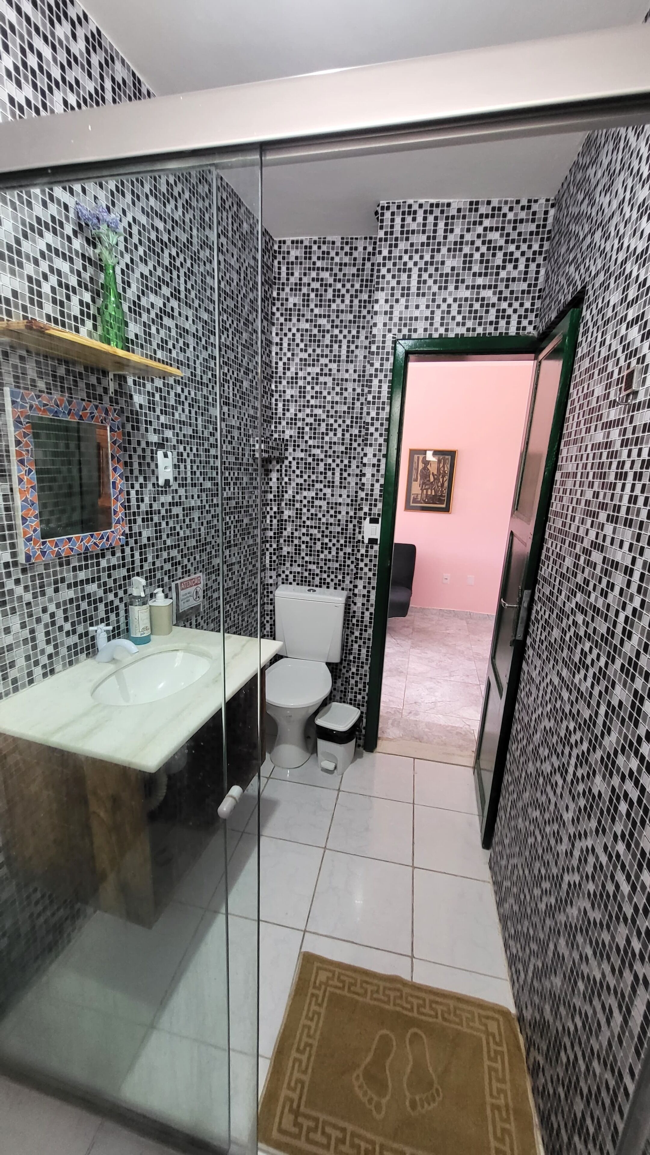 A bathroom with a glass partition, a sink, a toilet, and a shower area.
