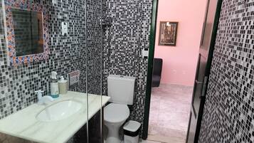 A bathroom with a glass partition, a sink, a toilet, and a shower area.