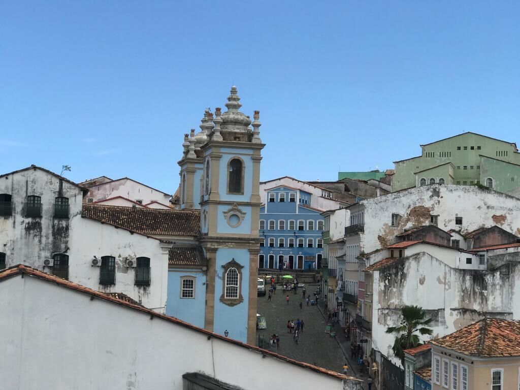 Une rue historique, avec un clocher d’église imposant et des bâtiments aux couleurs vives.