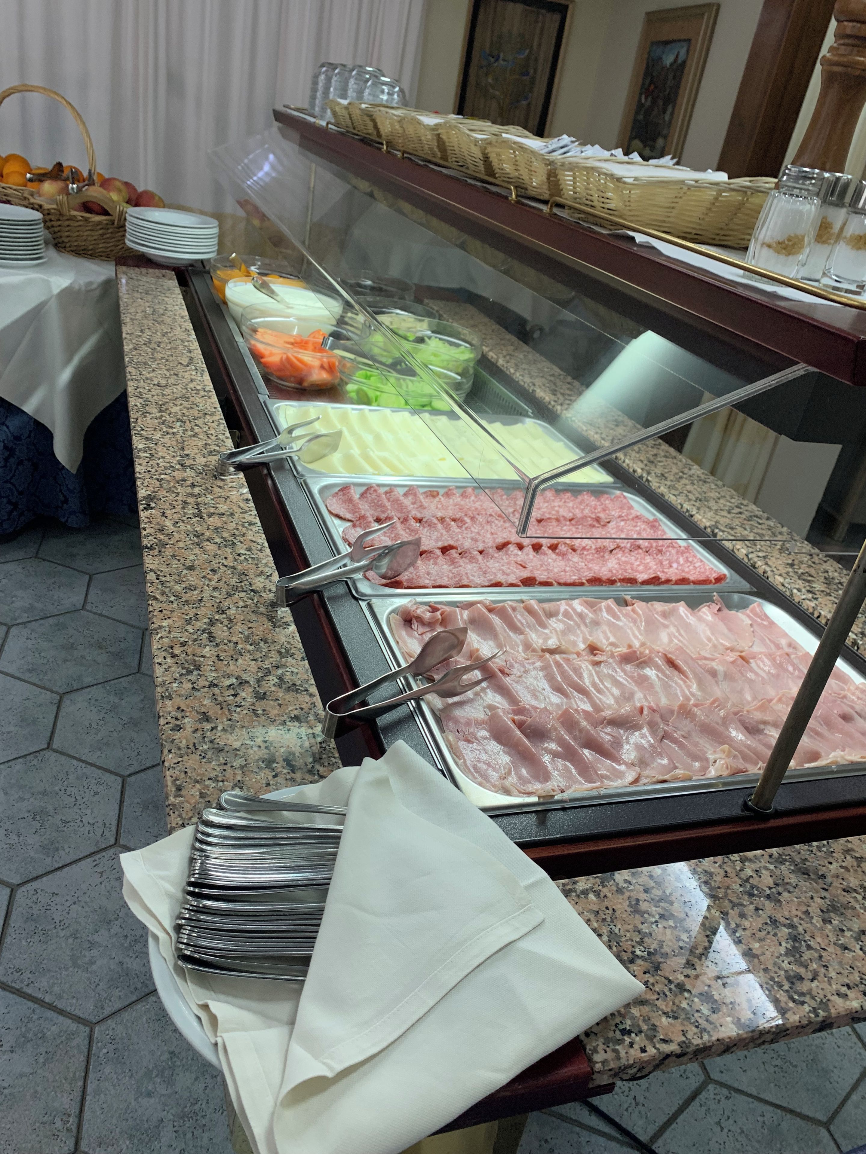 Ein Buffet mit verschiedenen Speisen, darunter Aufschnitt und frisches Gemüse.