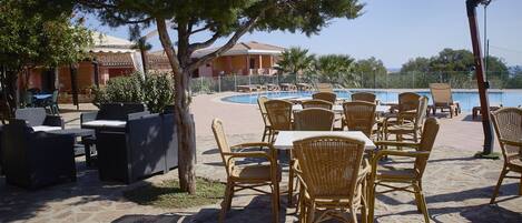 Un espace piscine extérieur aménagé avec des meubles en osier et offrant une vue sur la mer.