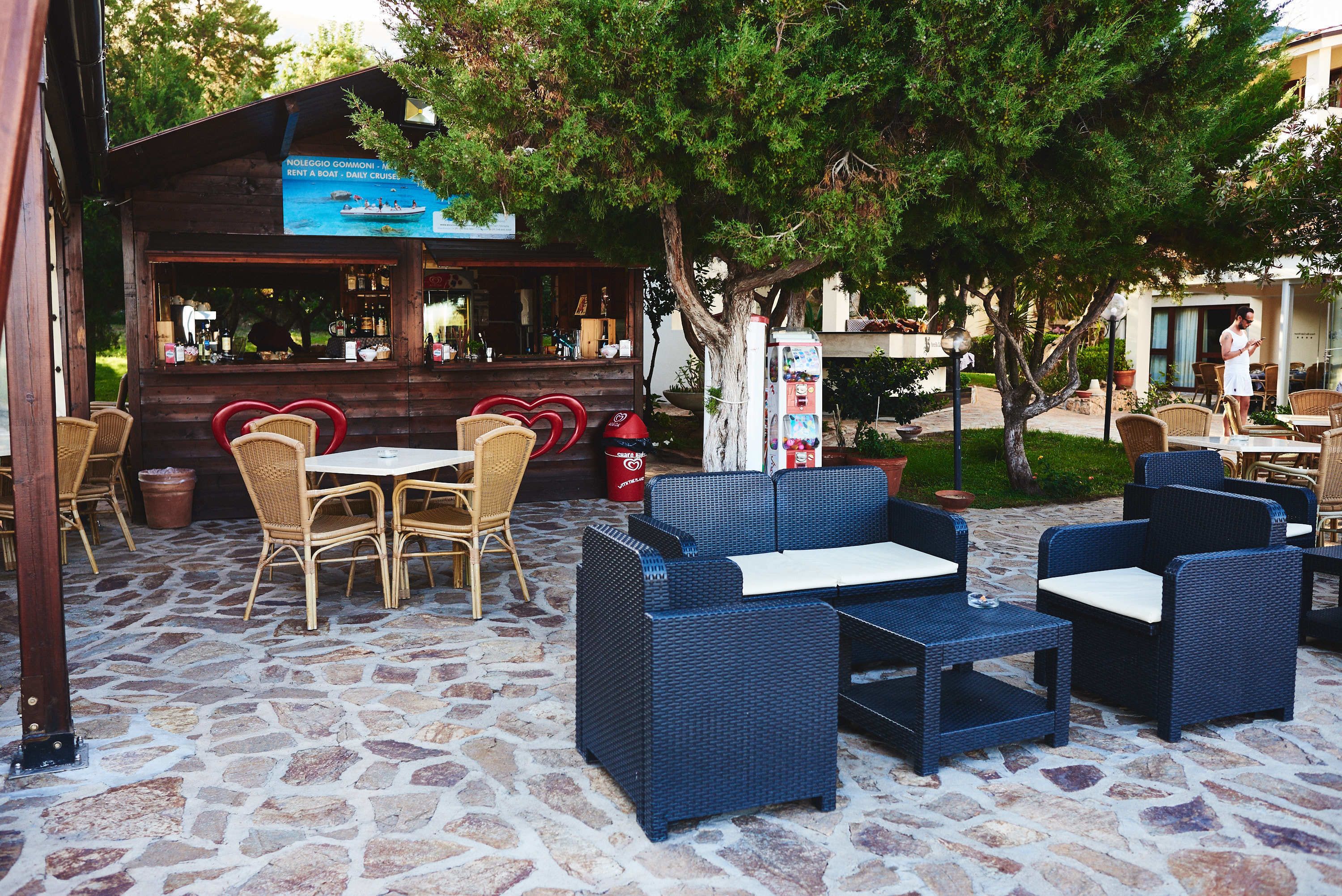 An outdoor seating area with wicker furniture and a stone floor.