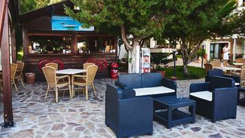 An outdoor seating area with wicker furniture and a stone floor.