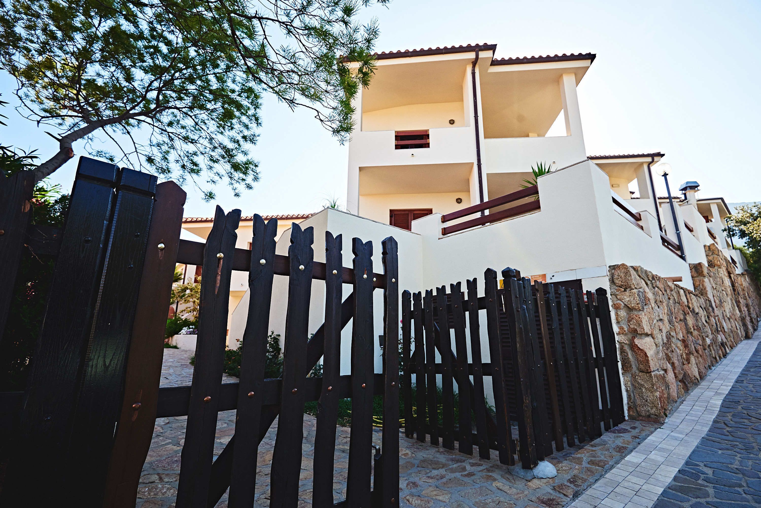 A modern two-story building with a stone wall and a wooden fence.
