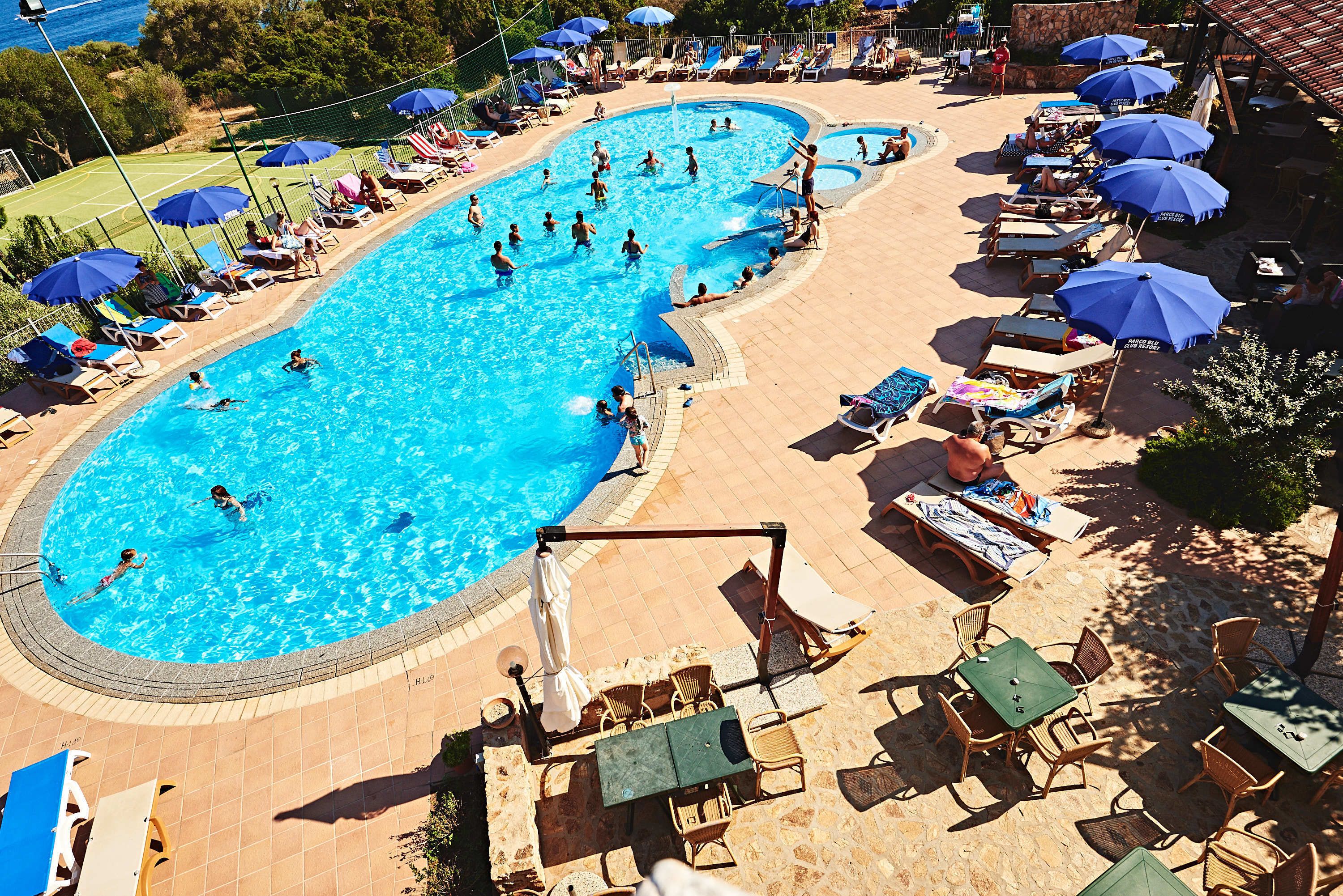 A large outdoor swimming pool surrounded by lounge chairs and umbrellas.