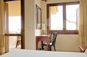 Habitación de hotel con cama, escritorio con silla, ventana y espejo.