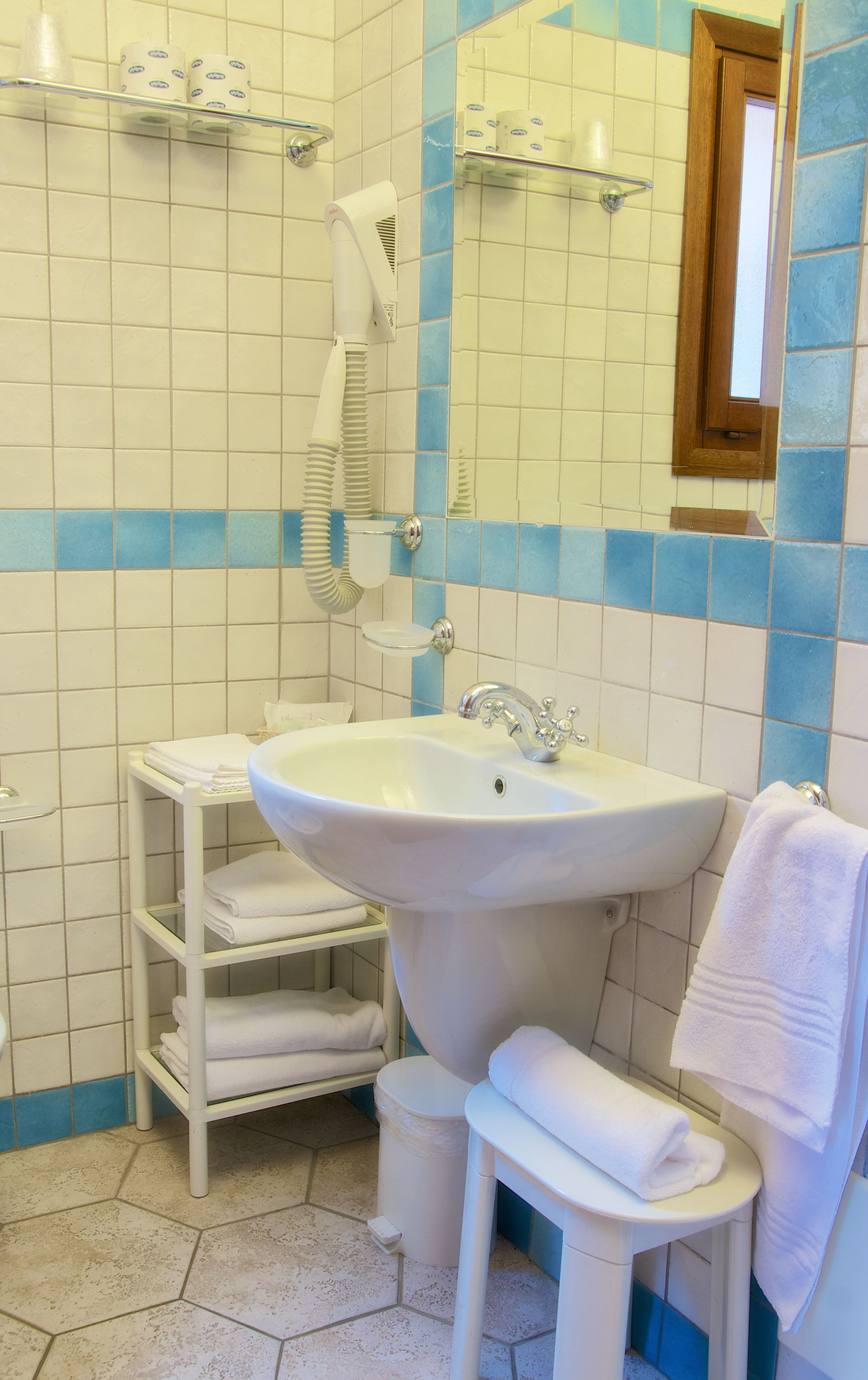 Ein Badezimmer mit einem weißen Waschbecken, einem Spiegel und einem Handtuchhalter.