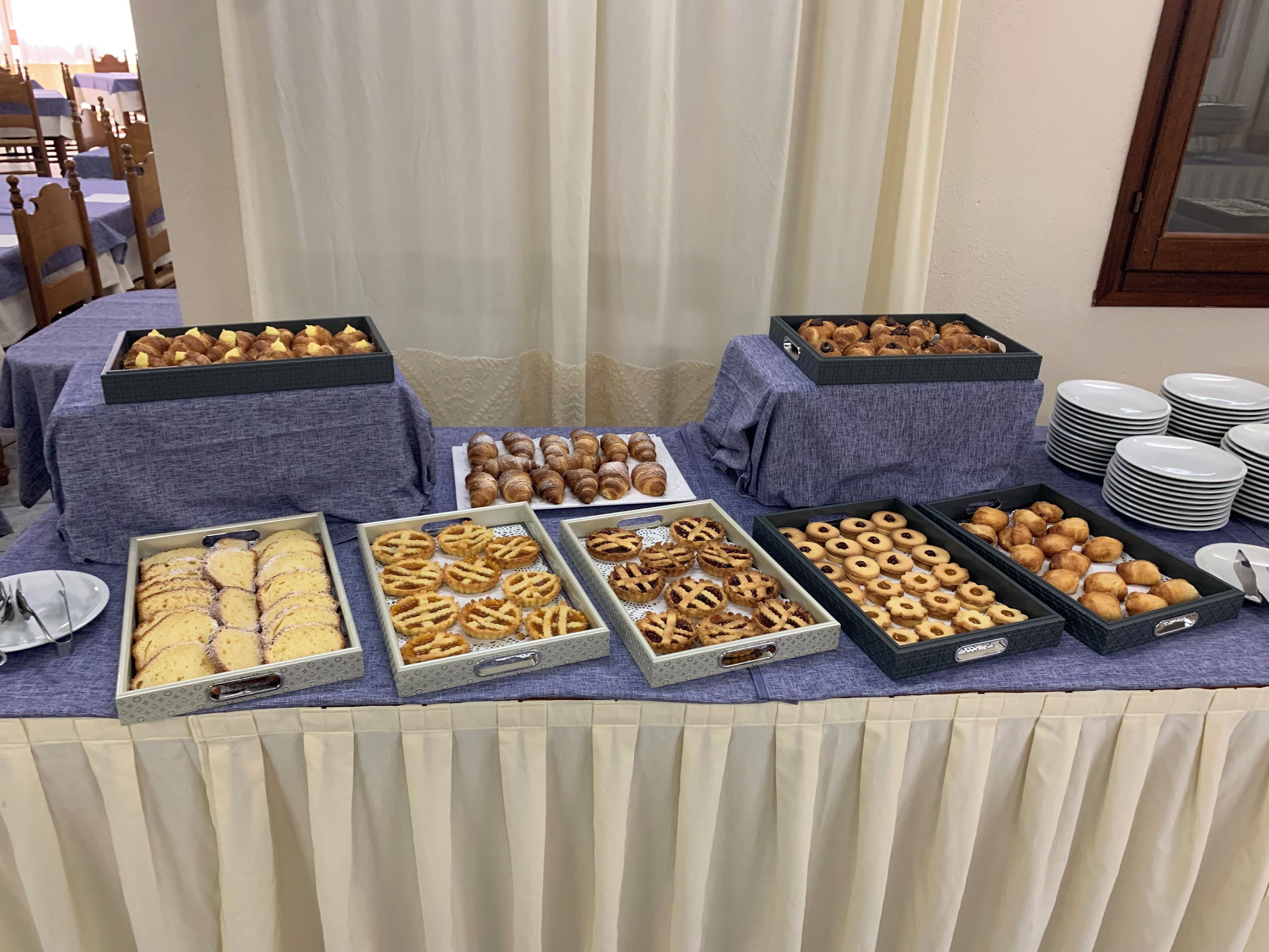 A buffet table with various baked goods and plates.