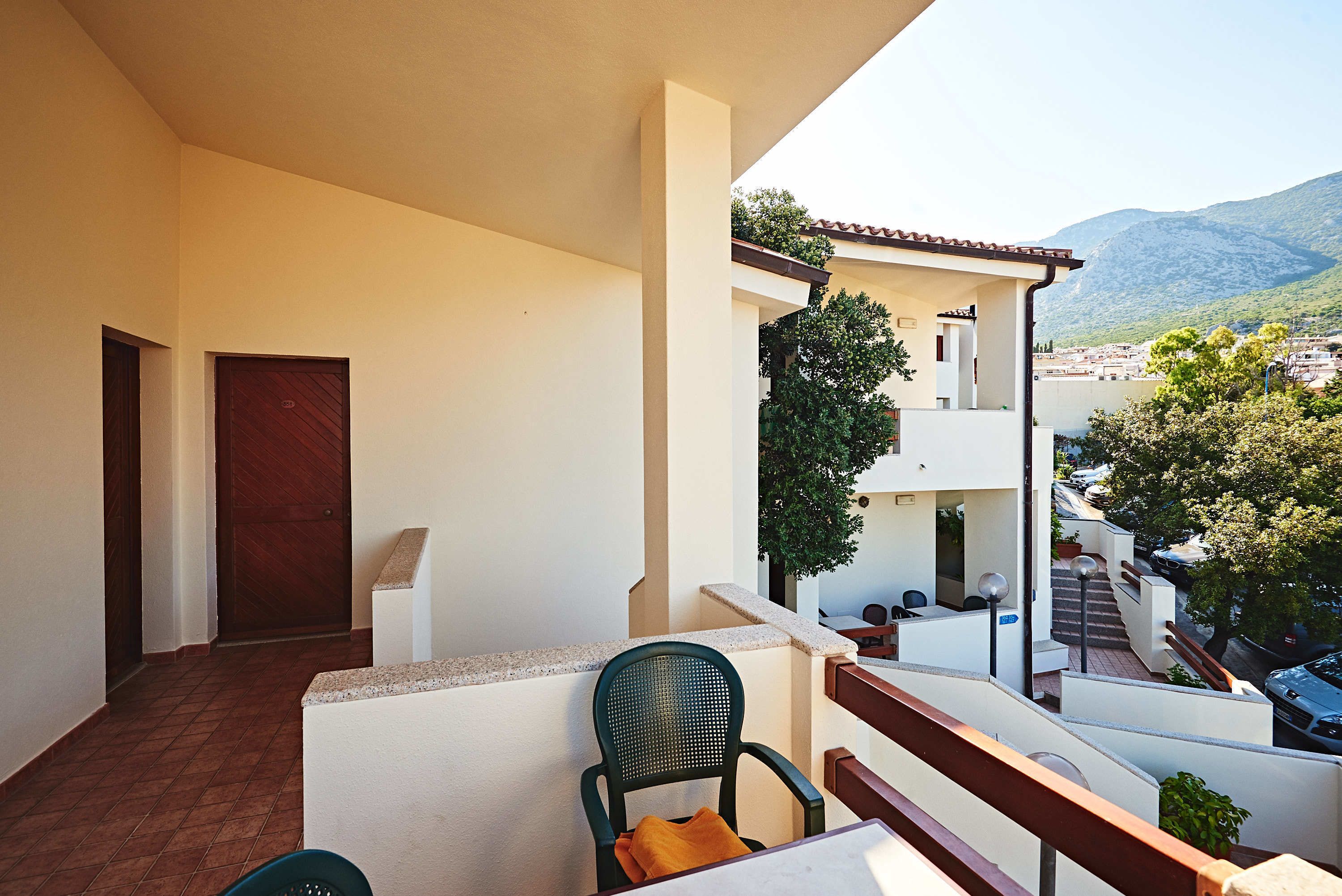 Un balcón con una silla, una mesa y vistas a un pueblo y montañas.