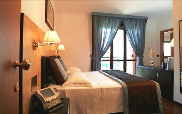 A hotel room with a bed, bedside lamps, a telephone, and a window with curtains. - Air Hotel (Forlì)