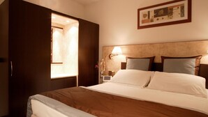 Una habitación de hotel con una cama, una mesita de noche, una lámpara y un cuadro en la pared.