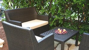 Un espacio al aire libre con mobiliario de mimbre y una pequeña mesa con fruta.