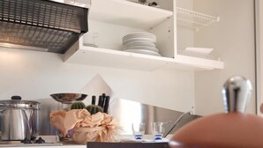 Cocina con armarios blancos, extractor de acero inoxidable y encimera con un tarro de harina, un paño y galletas.
