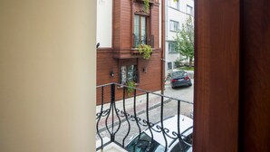A view from a balcony overlooking a street with a brick building, a parked car, and a white car in the foreground. - Berce Hotel (Istanbul)