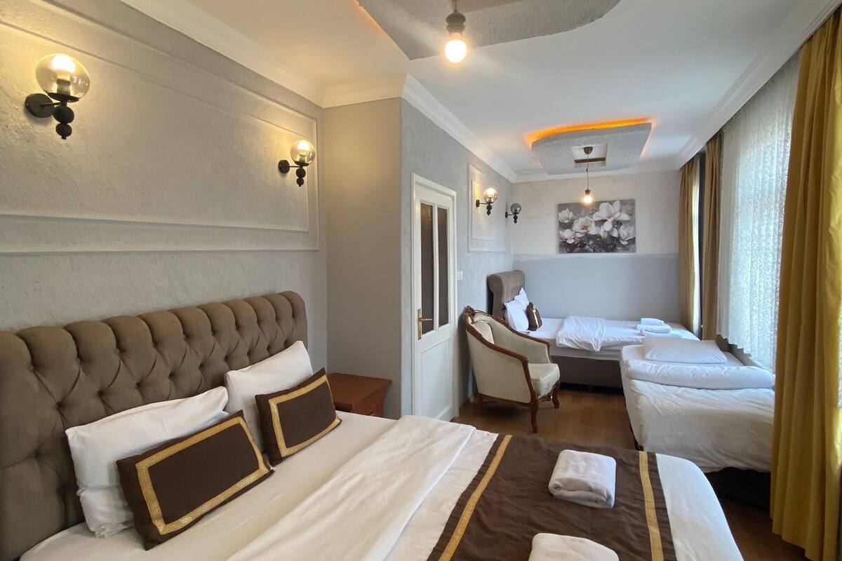A hotel room with a large bed, a smaller bed, a chair, and a painting on the wall.