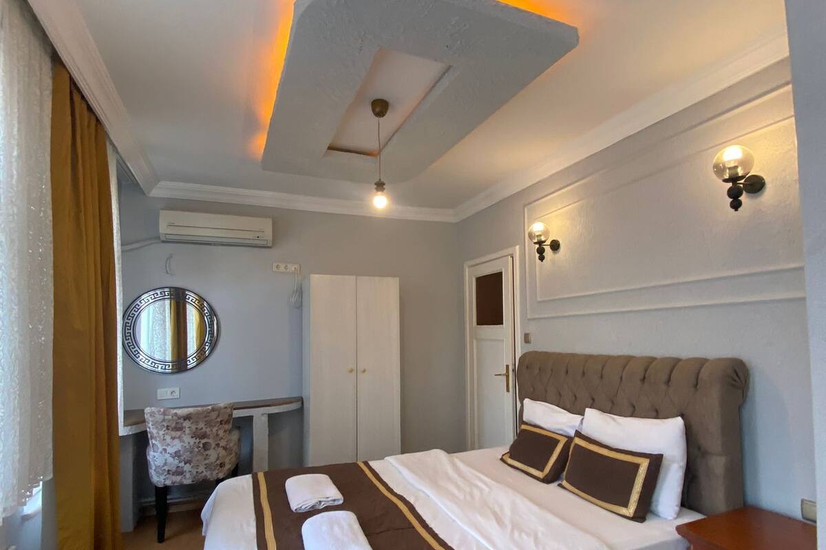 A hotel room with a large bed, a desk, and a chair.