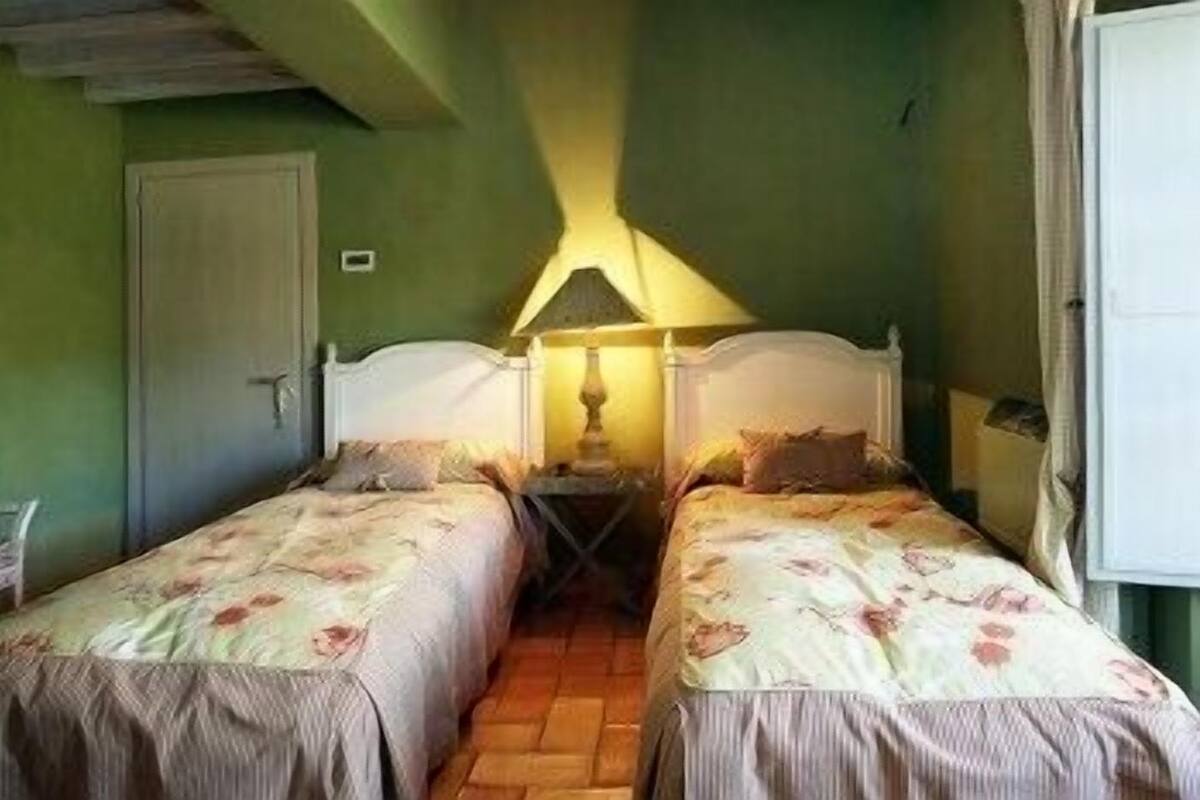 A room with two single beds, a nightstand with a lamp, and a door.