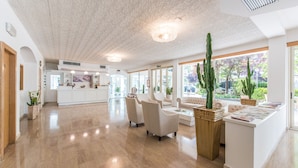 A spacious, well-lit hotel lobby with a polished wooden floor, comfortable seating areas, and large windows offering views of the outdoors. - Michelangelo (Cesenatico)