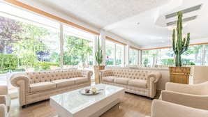 A spacious living room with a large window, a glass coffee table, and two beige sofas. - Michelangelo (Cesenatico)