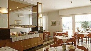 Un espace repas avec des tables dressées pour les repas, un grand miroir et une vue sur l’extérieur.