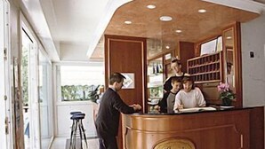 Un espace d’accueil avec un comptoir en bois portant l’inscription « Paris », un bar avec des tabourets et une vue sur l’extérieur grâce à de grandes fenêtres.