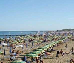 A crowded beach with numerous umbrellas and people. - Hotel Paris (Lignano Sabbiadoro)