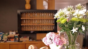 A reception desk with a display of glassware, a vase with flowers, and a decorative shell. - Hotel Santiago (Jesolo)