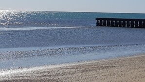 A beach with a wooden pier extending into the water. - Hotel Santiago (Jesolo)