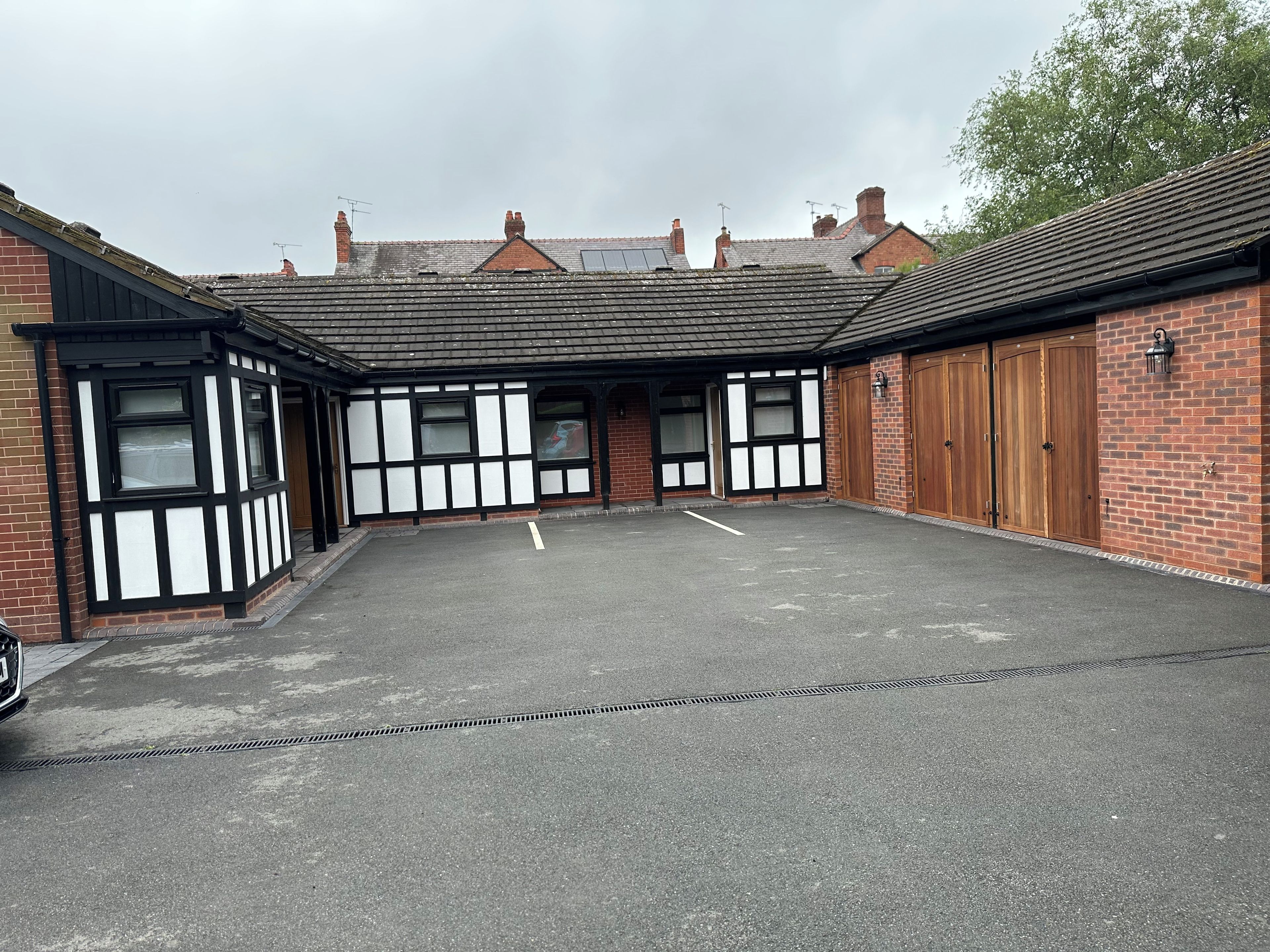A building with a courtyard, featuring a mix of brick and timber framing, and a large open space in front.