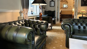 A living room with leather sofas, a lamp, a violin, and a clock on the wall.