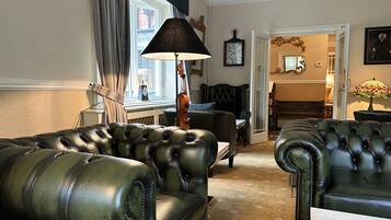 A living room with leather sofas, a lamp, a violin, and a clock on the wall.