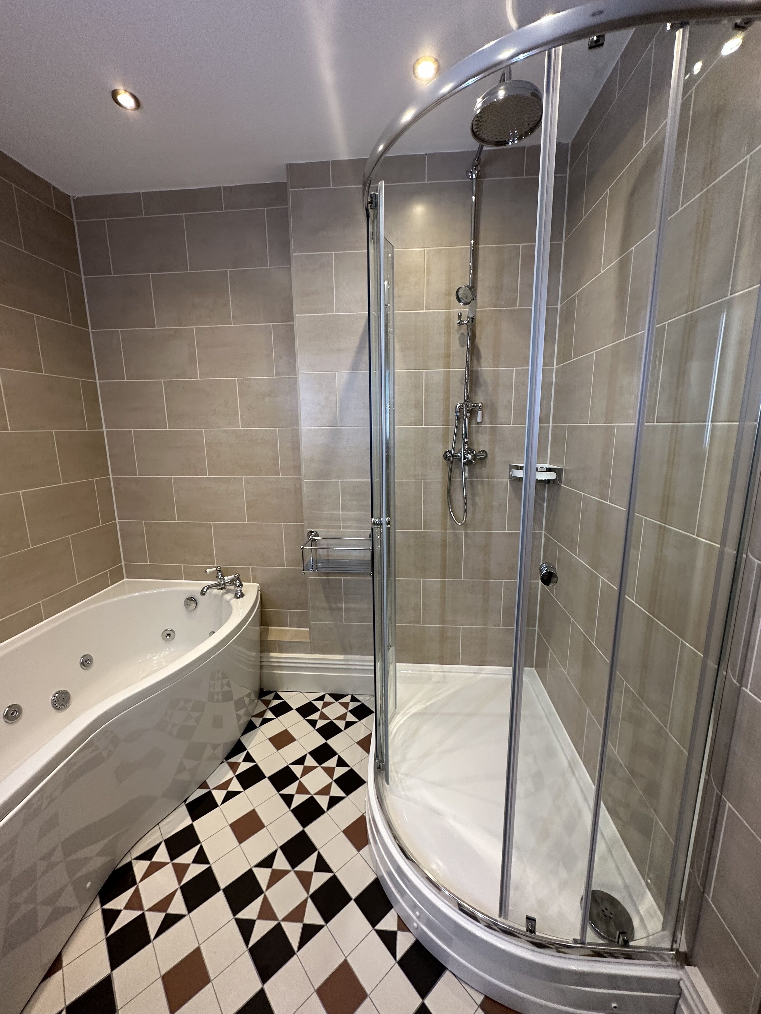 A modern bathroom with a freestanding bathtub, a glass-enclosed shower, and a checkered floor.