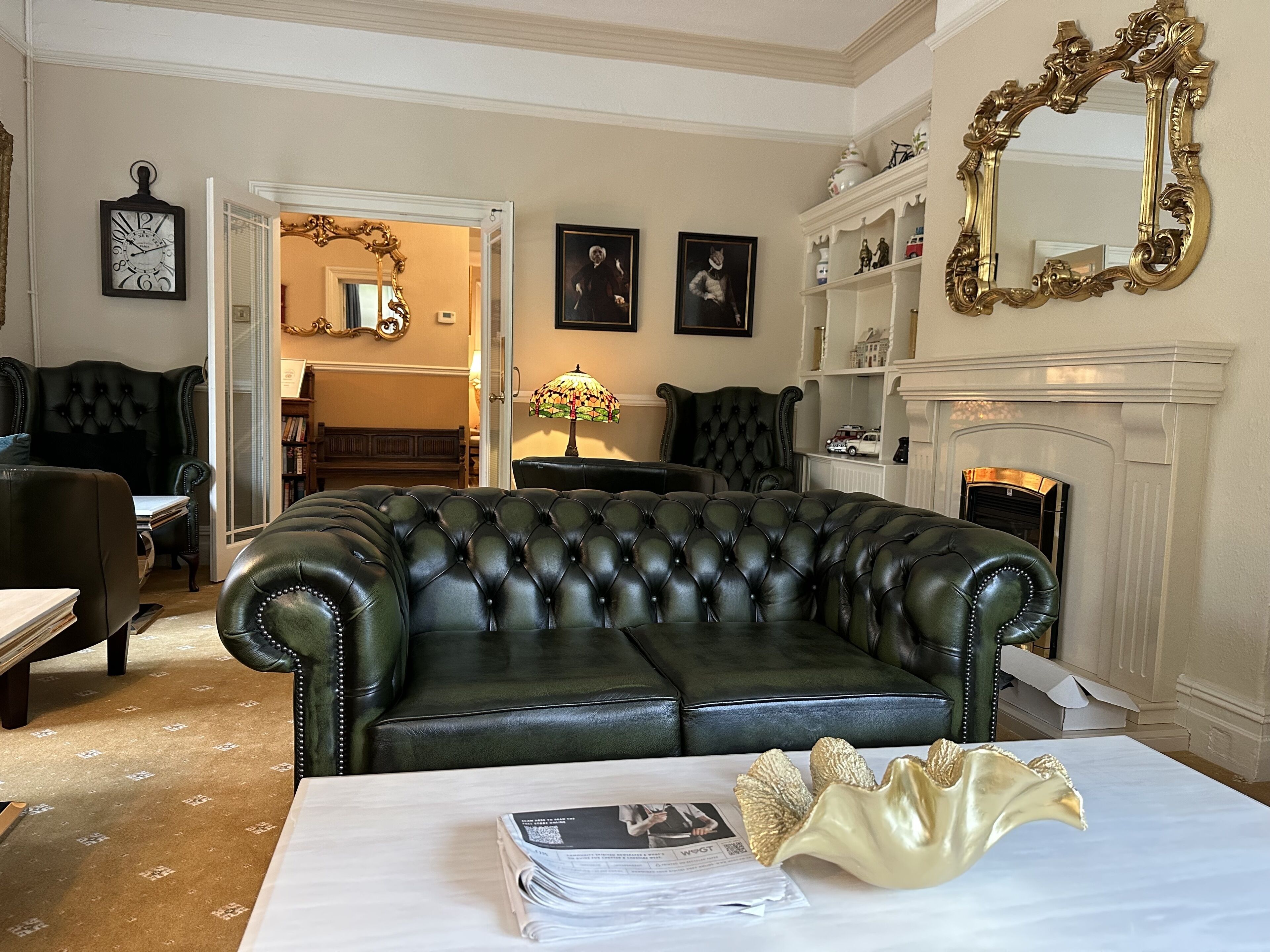 Un salon avec un canapé en cuir noir, une table blanche et une cheminée.