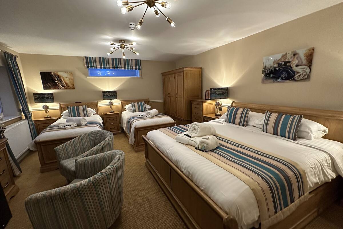 A hotel room with two beds, a large window, a ceiling fan, and a painting on the wall.