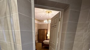 A hallway with a patterned floor, a wooden wardrobe, and a door leading to a bedroom. - Chester House Guest House (Chester)