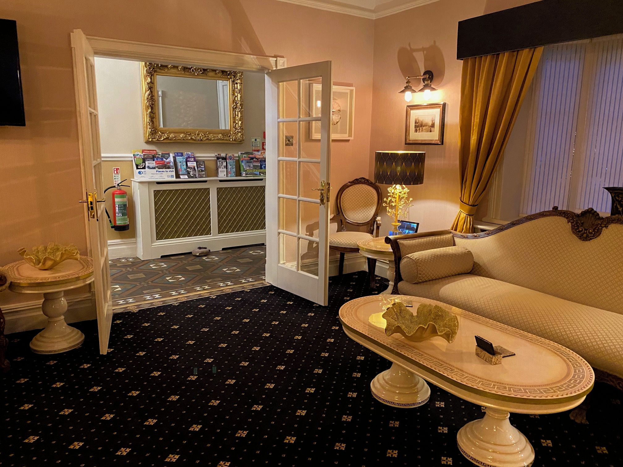 A hotel room with a dining area, a sofa, a coffee table, a mirror, and a door leading to a bathroom.