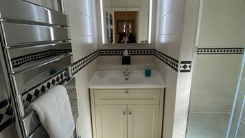 Un baño con ducha, lavamanos y espejo.