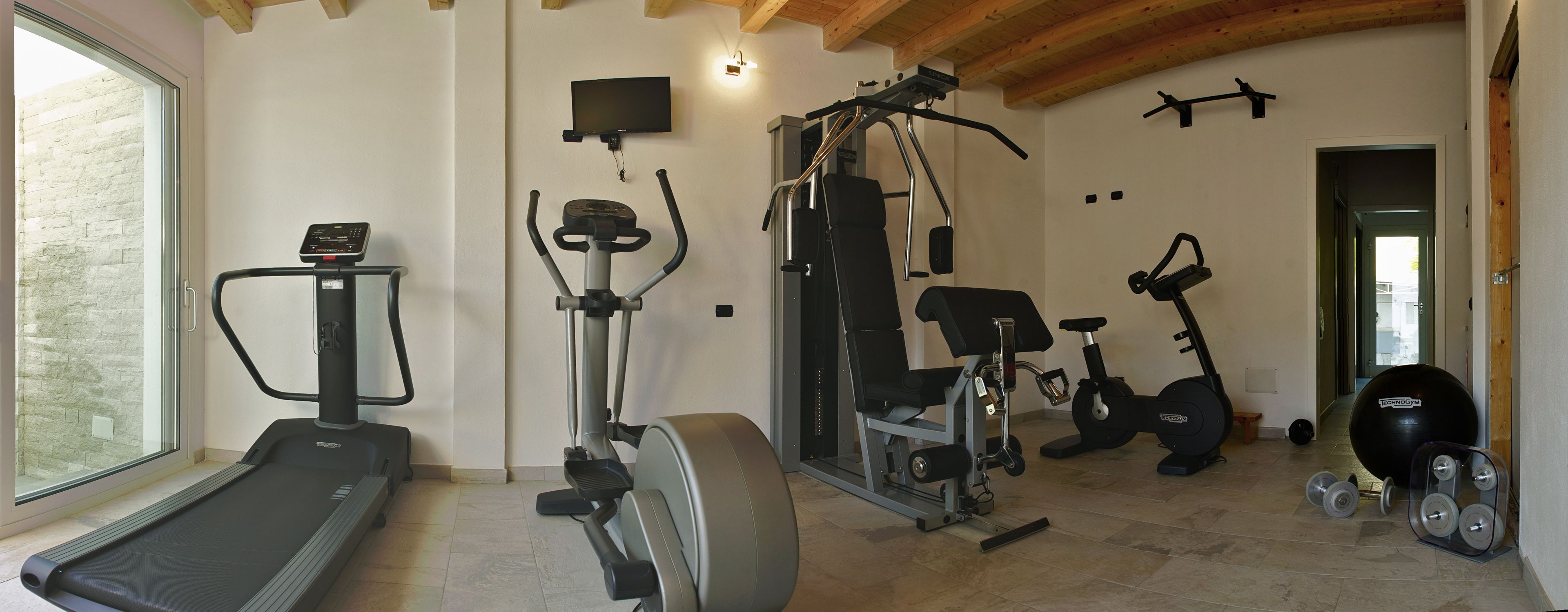 A home gym with a treadmill, elliptical, stationary bike, and various exercise machines.