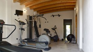 Een sportruimte met een loopband, elliptische trainer en krachttoestellen.